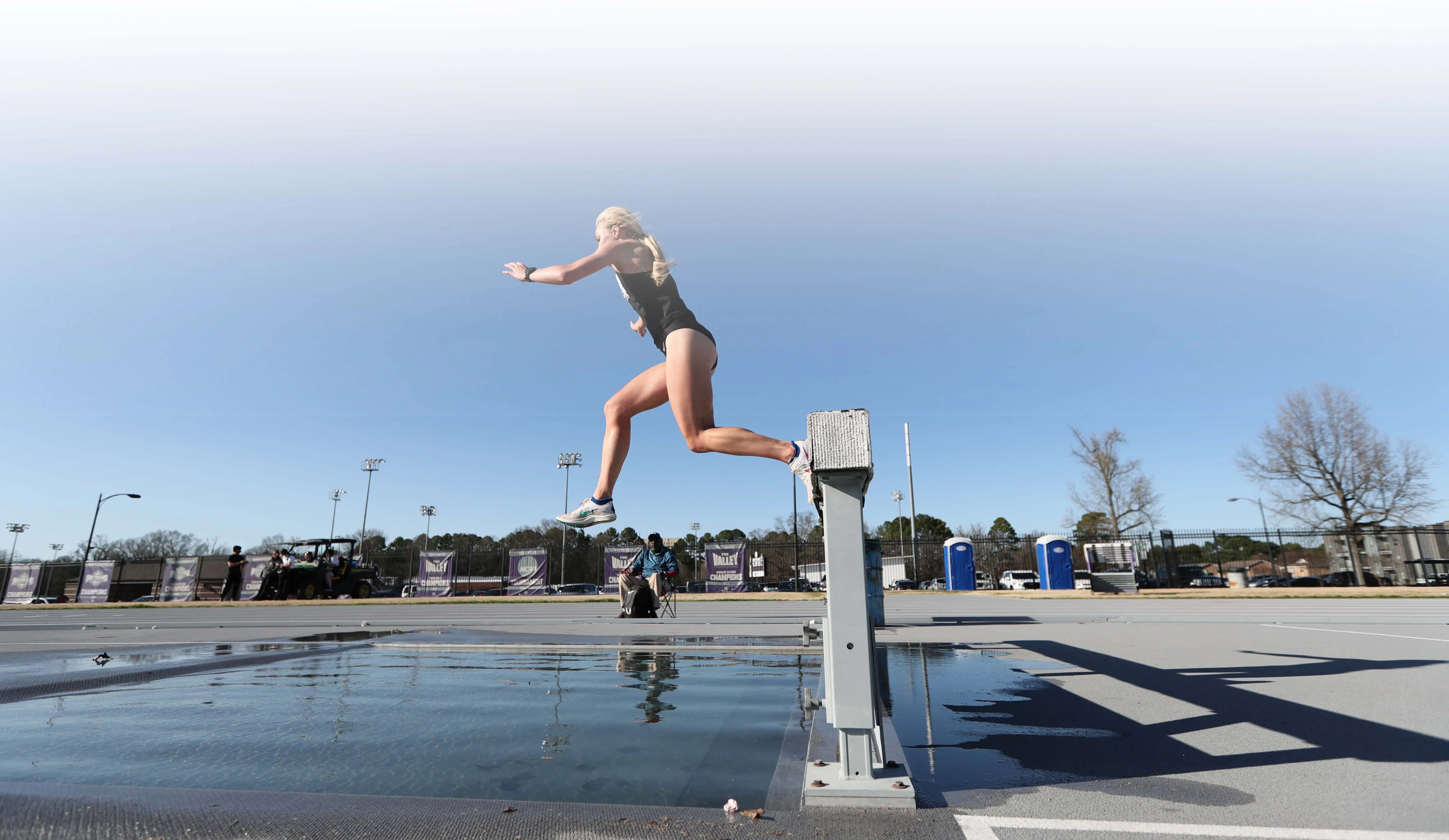 Track athlete jumping water hurdle